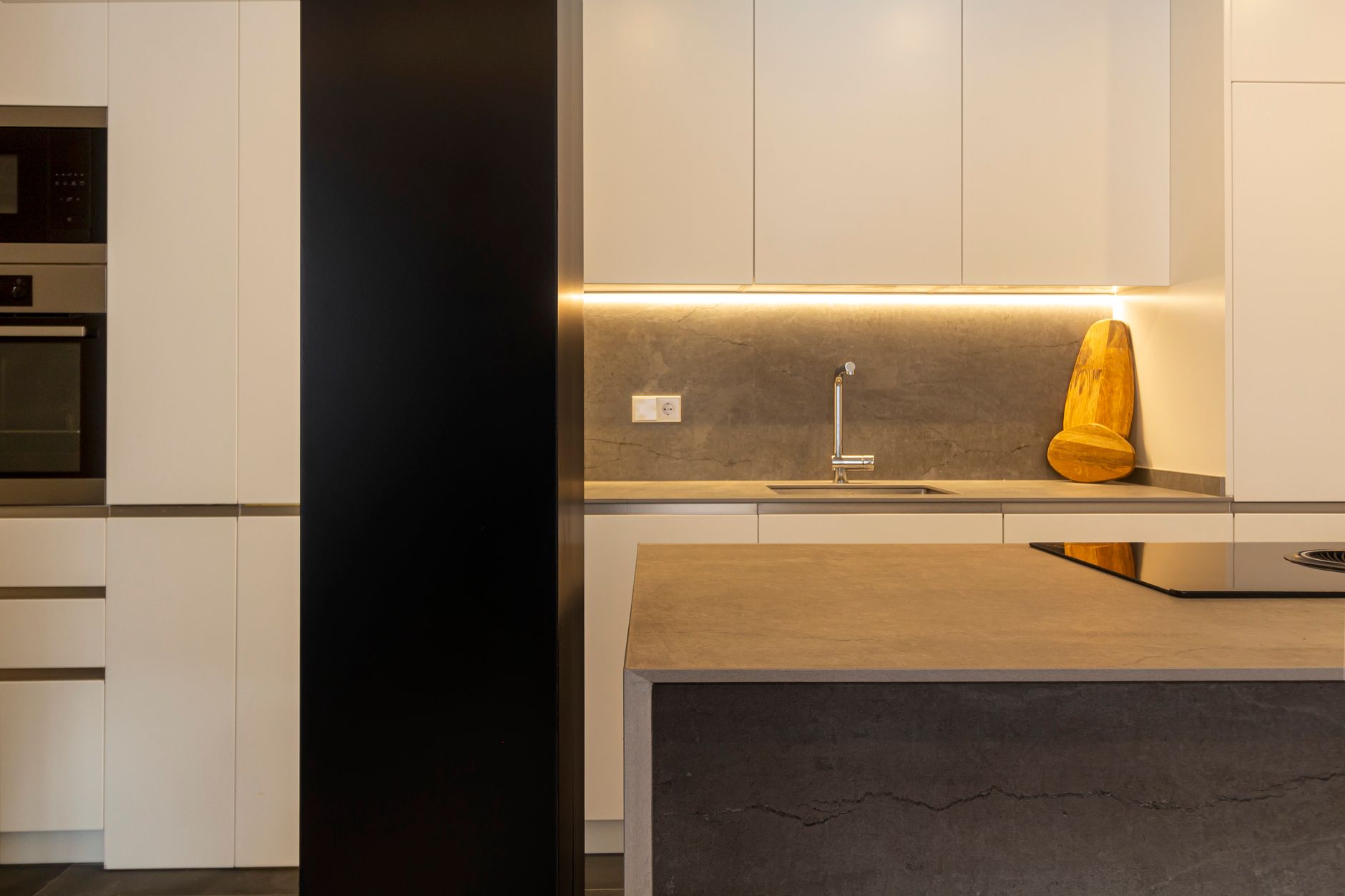 A stylish kitchen featuring modern design with minimalist elements and warm lighting.